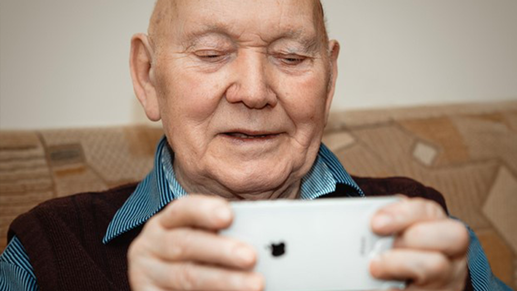 Elderly Gentleman Facetiming On An iPhone - Long-Distance Caregiving